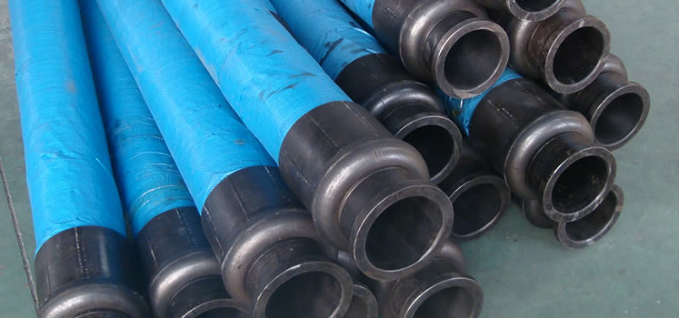 Many blue steel wire reinforced concrete pump hoses are on the floor of the workshop.